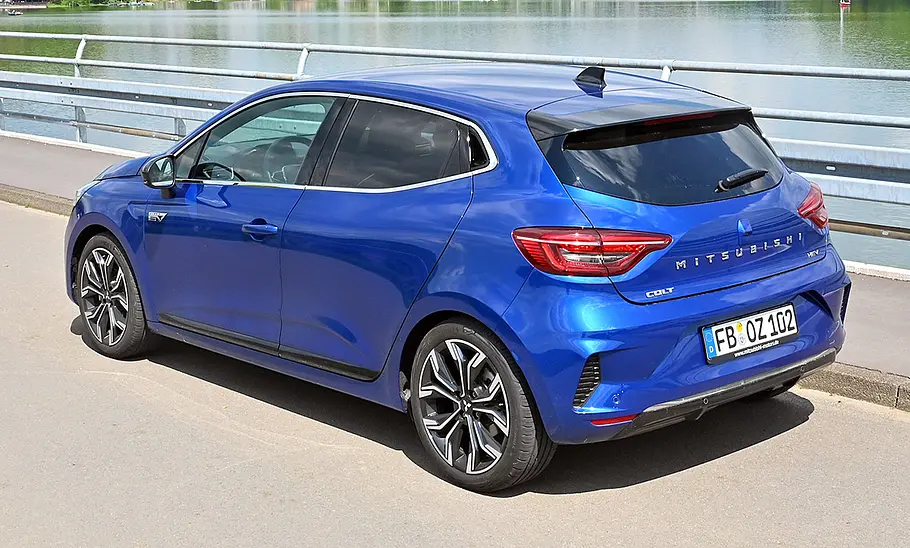 Mitsubishi Colt Hybrid 1.6 statisch von schräg hinten auf einer Straße an einem Fluss.