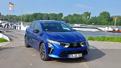 Mitsubishi Colt Hybrid 1.6 steht auf einer Straße an einem Fluss, Ansicht von vorne rechts. - Foto: Nils Koshofer