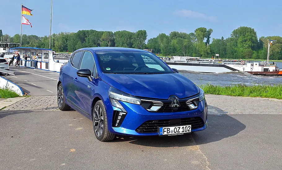 Mitsubishi Colt Hybrid 1.6 steht auf einer Straße an einem Fluss, Ansicht von vorne rechts.