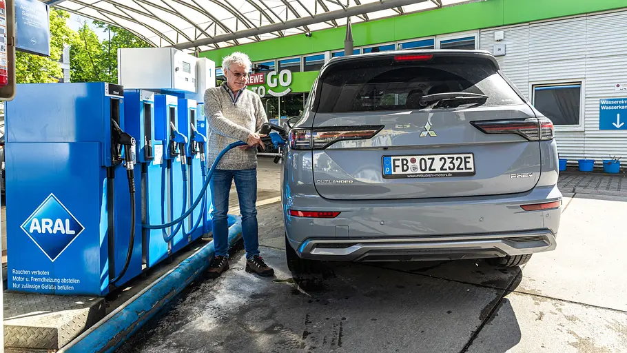 Mitsubishi Outlander wird von einer Person an einer Aral-Tankstelle betankt. Ansicht des Fahrzeugs von hinten.