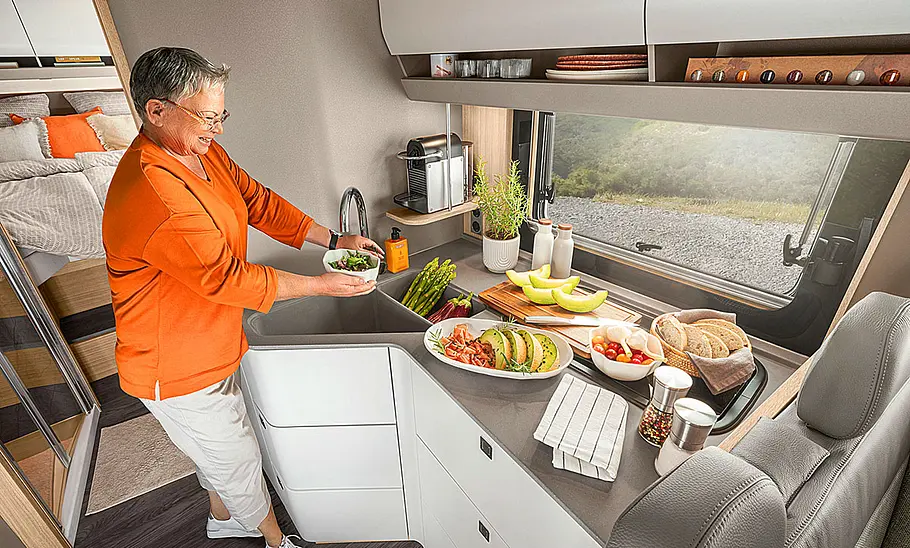 Das Bild zeigt die Küche des Morelo Loft (2024). Eine Person wäscht Gemüse in der Spüle. Auf der Arbeitsfläche stehen Lebensmittel.