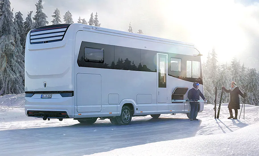 Morelo Palace Der Morelo Palace (2024) statisch mit Ansicht von schräg hinten rechts. Das Wohnmobil parkt im Schnee, zwei Personen mit Skier stehen daneben.