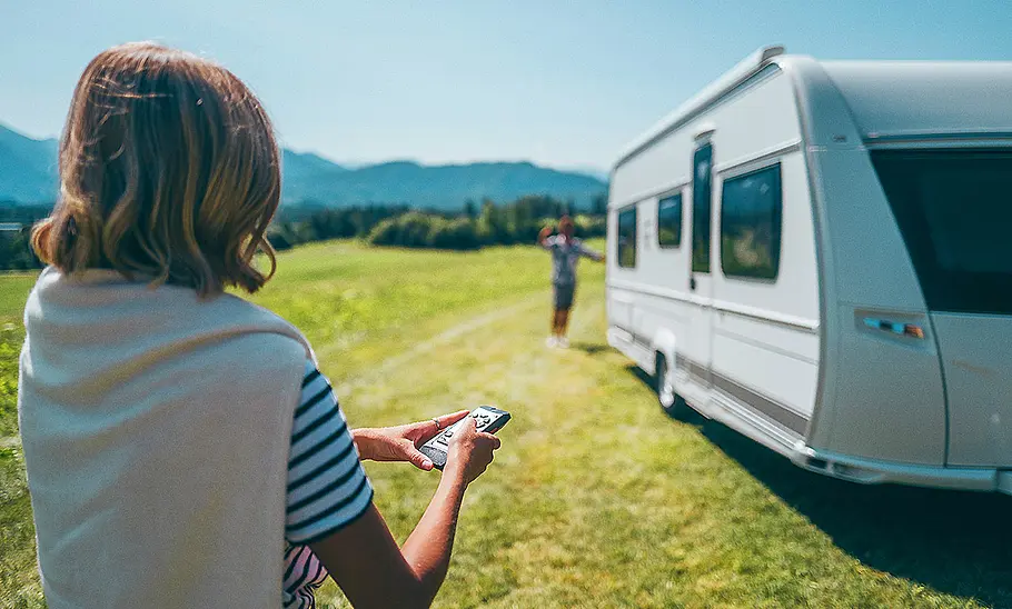 Man sieht ein Mover für Wohnwagen. Eine Person steuert einen Caravan mit Mover über eine Fernbedienung.