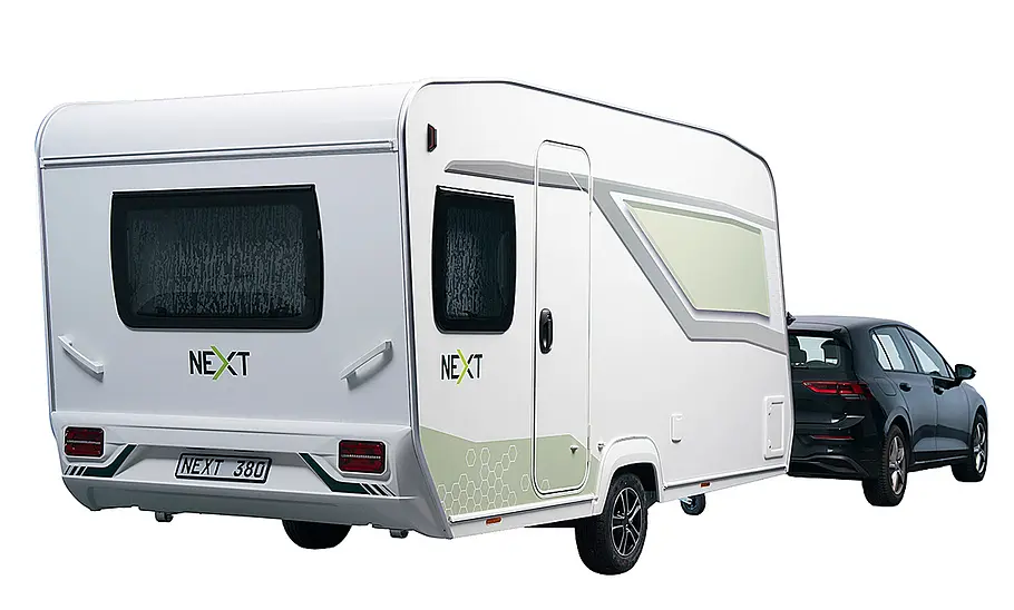 Das Bild zeigt den Next 380 (2025) stehend von schräg hinten rechts fotografiert. Der Caravan ist an einem VW Golf angehängt.