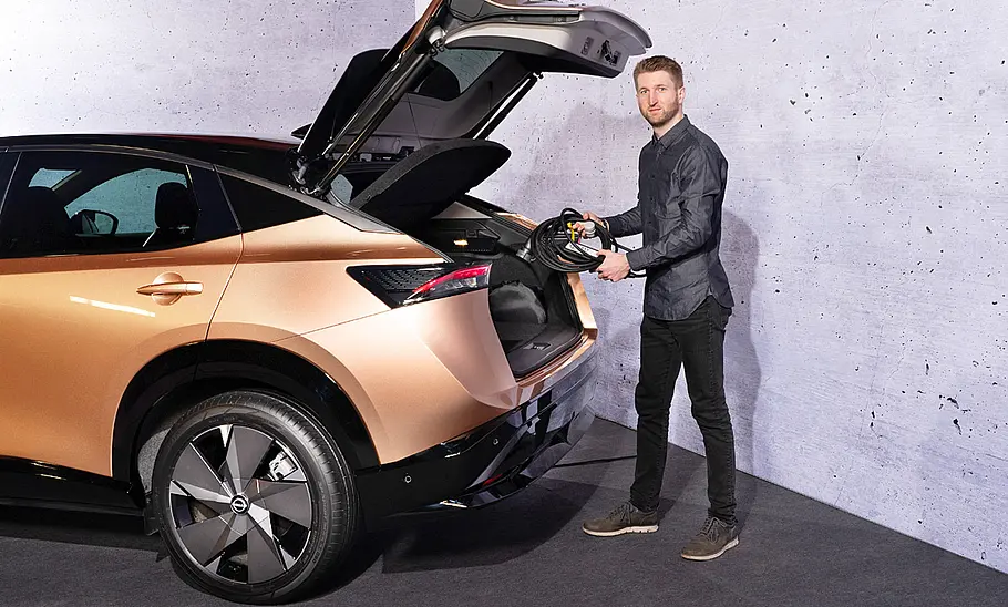 Nissan Ariya (2022) Nissan Ariya (2022); Blick von außen auf das Auto mit geöffneter Heckklappe. AUTO ZEITUNG-Chefredakteur Alexander Koch steht davor.