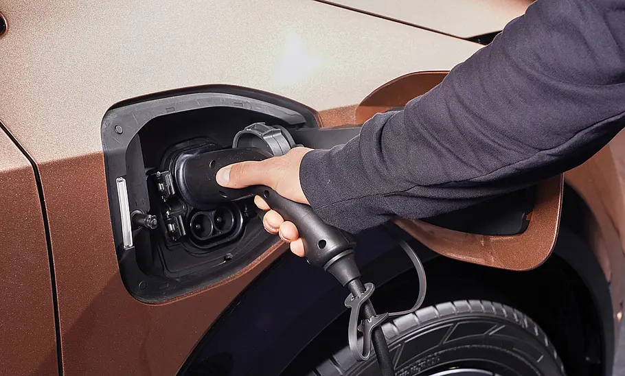 Nissan Ariya (2022) Nissan Ariya (2022); Detailansicht, wie jemand die Ladesäule in die Ladebuchse des Elektroautos steckt.