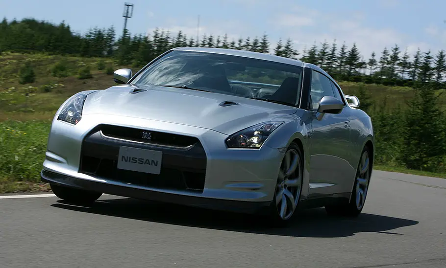 Nissan GT-R Der Nissan GT-R fahrend auf einer Straße, fotografiert von schräg vorne.