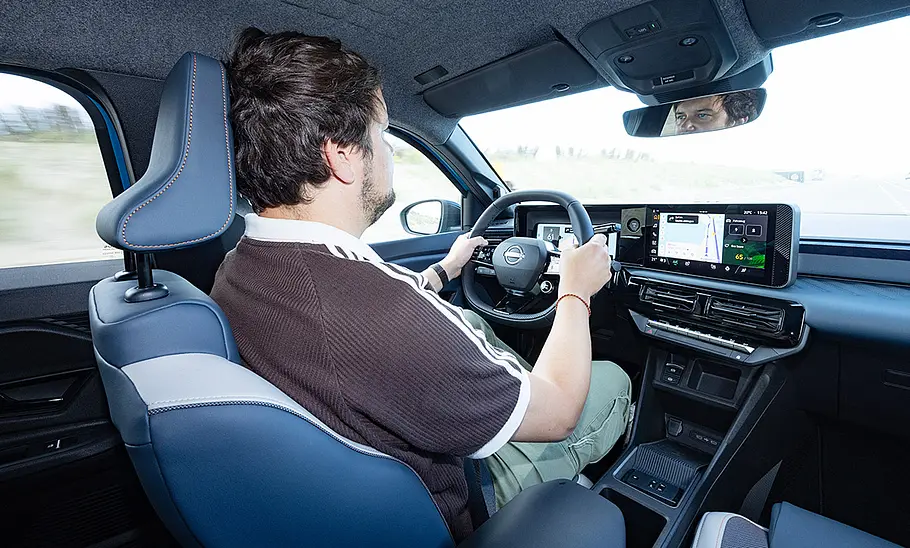AUTO ZEITUNG-Redakteur Sven Kötter am Steuer des Nissan Micra (2026), fotografiert von schräg über die Schulter mit Blick auf das Armaturenbrett.