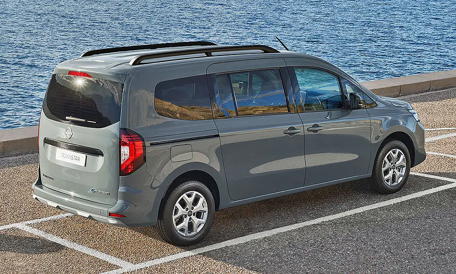 Nissan Townstar steht auf einem Parkplatz am Meer, Ansicht von hinten rechts.