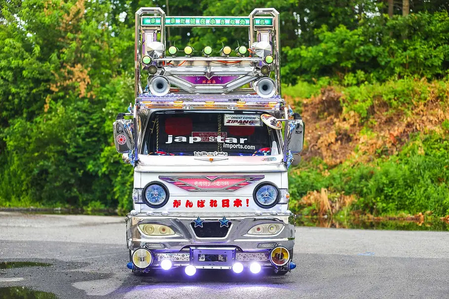 Der Suzuki Carry Dekotora steht vor einem Wald, fotografiert von vorne.
