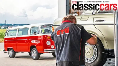 Ein Oldtimer-Gutachter untersucht einen Oldtimer (Mercedes). Im Hintergrund steht ein roter Bulli. - Foto: GTÜ