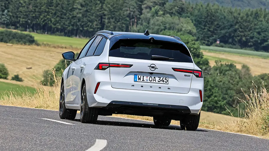 Der Opel Astra Sports Tourer durch eine Linkskurve fahrend von schräg hinten links fotografiert.