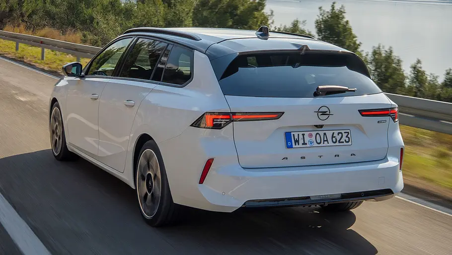 Der Opel Astra Sports Tourer fährt auf einer Landstraße, von hinten links fotografiert.