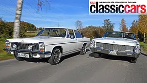 Das Opel Diplomat B Cabriolet und der Cadillac De Ville Convertible fahren nebeneinander auf der Landstraße, fotografiert von schräg vorne. - Foto: Jürgen Gassebner