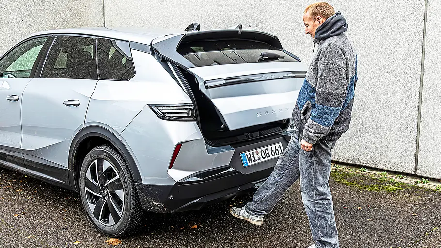 Blick von schräg hinten auf den Opel Grandland mit sich öffnender Heckklappe.