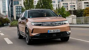 Der Ople Grandland auf einer Mainbrücke fahrend von schräg vorne links mit der Frankfurter Skyline im Hintergrund. - Foto: Opel