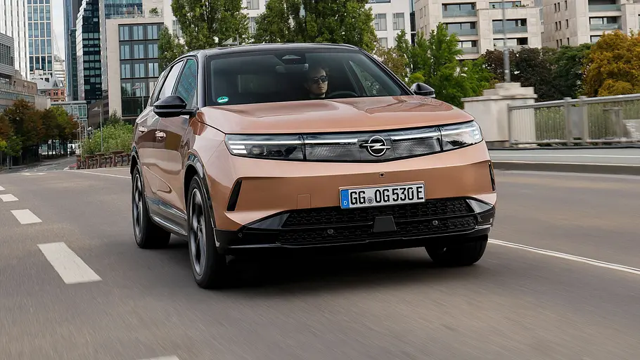 Opel Grandland Leasing-News Der Opel Grandland auf einer Mainbrücke fahrend von schräg vorne links mit der Frankfurter Skyline im Hintergrund.