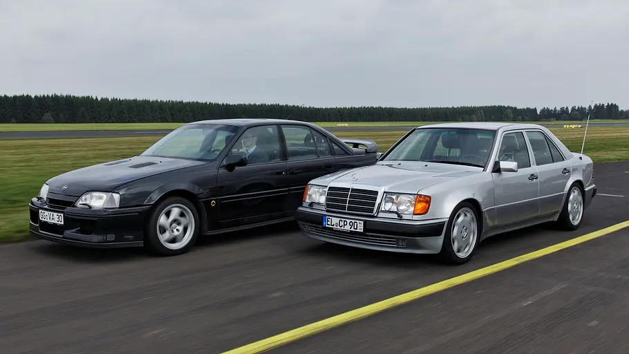 Opel Lotus Omega und Mercedes 500 E fahrend von schräg vorne.