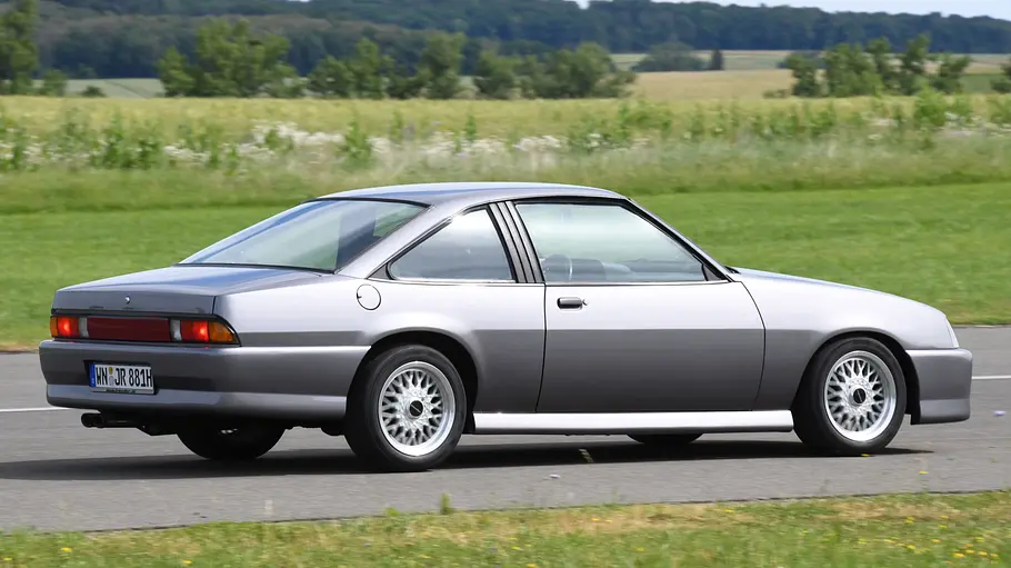 Der Opel Manta C fahrend von schräg hinten.
