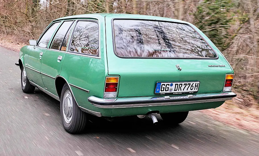Der Opel Rekord D Caravan fahrend von schräg hinten