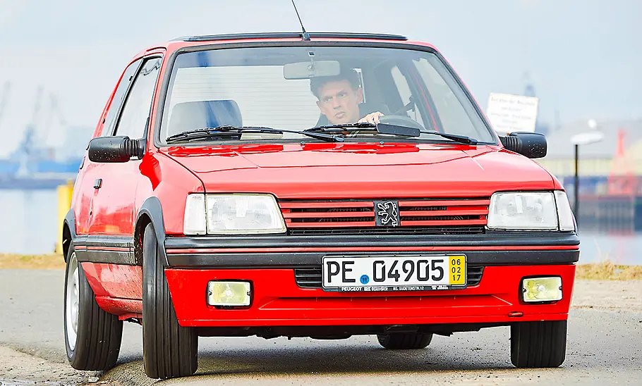 Der Peugeot 205 GTi fahrend von schräg vorne fotografiert.