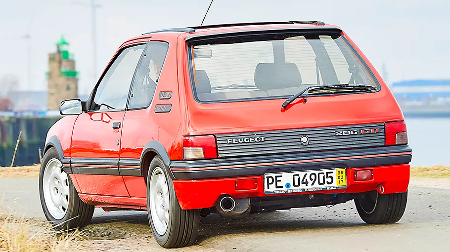 Der Peugeot 205 GTi fahrend von schräg hinten fotografiert.