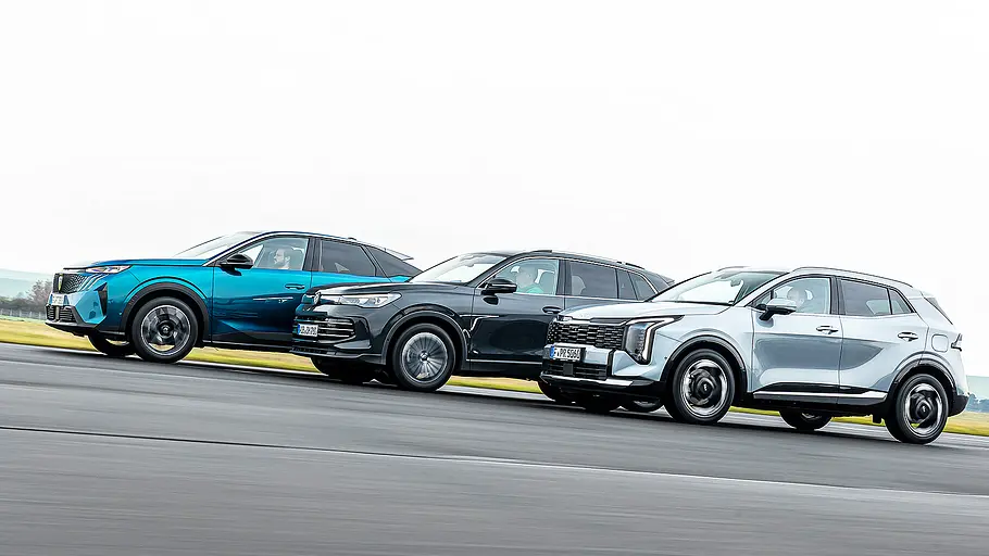 Blick von der Seite auf die drei fahrenden Kompakt-SUV Peugeot 3008, VW Tiguan und Kia Sportage.