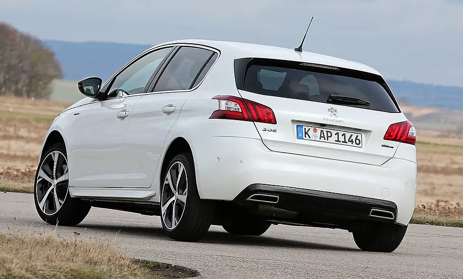 Der Peugeot 308 fährt durch eine Kurve, fotografiert von hinten.