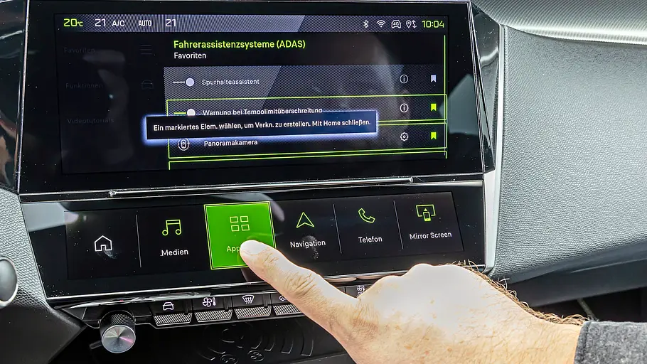 Ein Finger zeigt auf die i-Toggles genannten Touch-Flächen des Peugeot-308-Infotainments in der Mittelkonsole.
