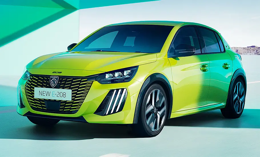 Das Peugeot E-208 Facelift (2023) fahrend von schräg vorne.