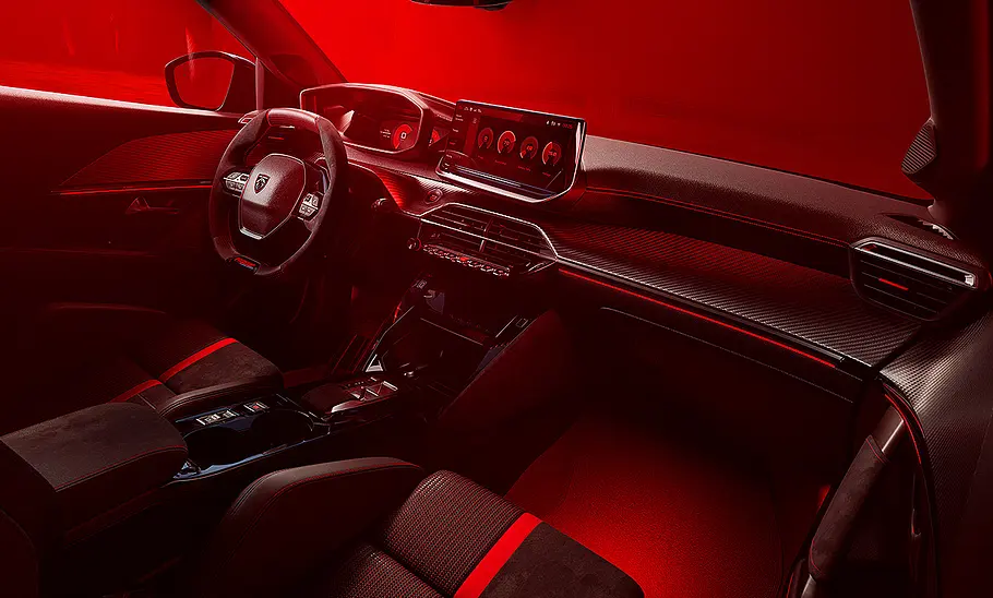 Blick auf die Armaturen im Innenraum des Peugeot E-208 GTi in rotem Licht.
