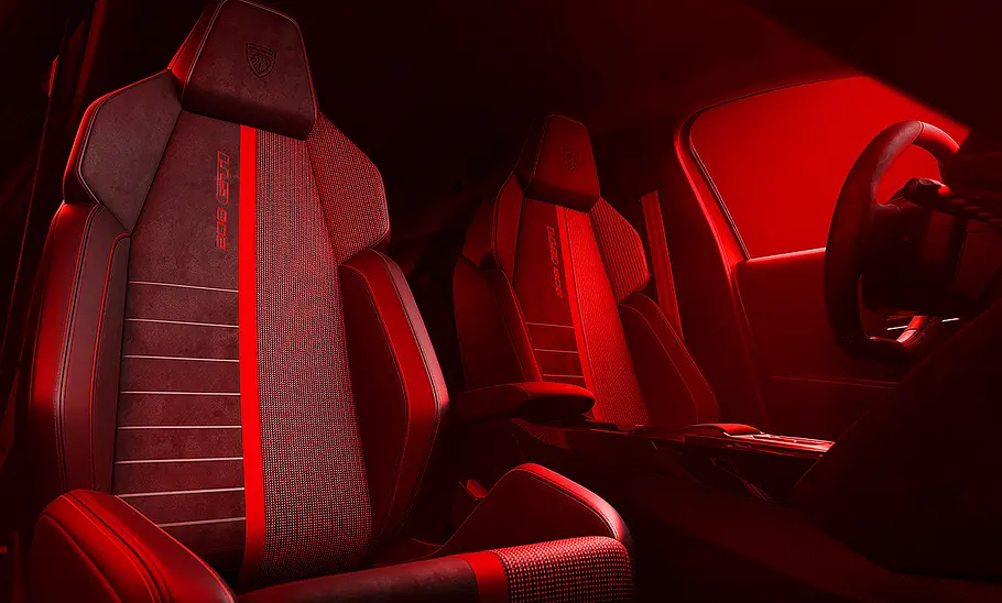 Blick auf die Vordersitze im Innenraum des Peugeot E-208 GTi in rotem Licht.
