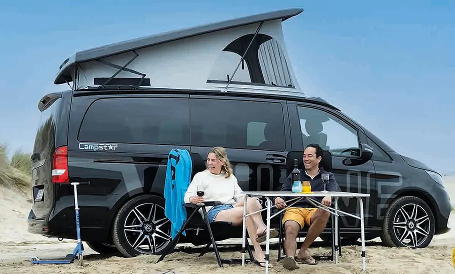 Die Außenaufnahme zeigt eine Frau und einen Mann vor dem geparkten Pössl Campstar (2025) schräg seitlich am Strand.