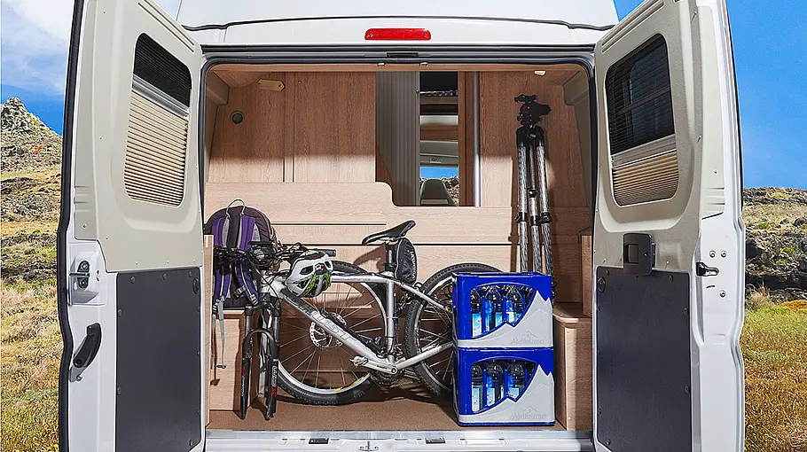 Pössl Vario 545 Das Bild zeigt die Heckgarage des Pössl Vario 545 (2024) mit ausgebautem Bett durch die geöffneten Hecktüren fotografiert.