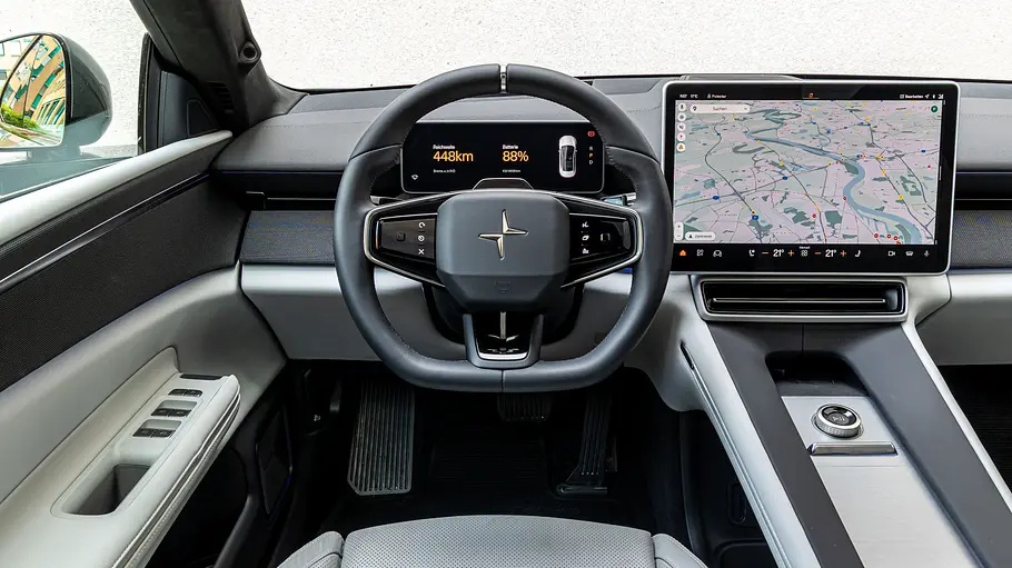 Das Cockpit des Polestar 4 mit Lenkrad, digitaler Instrumentenanzeige, großem Navigationsdisplay und heller Mittelkonsole ist zu sehen.