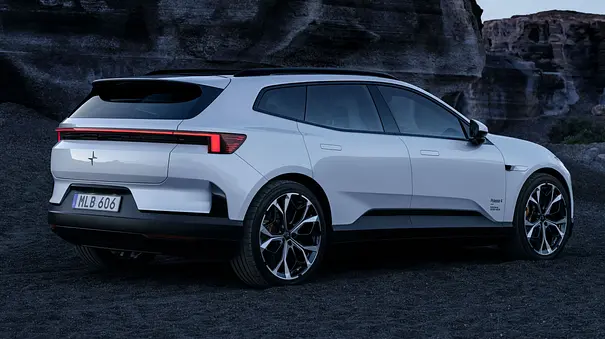 Polestar 4 SUV vor einer Klippe im Sand, Ansicht der Fahrzeugs von hinten rechts. - Foto: Polestar