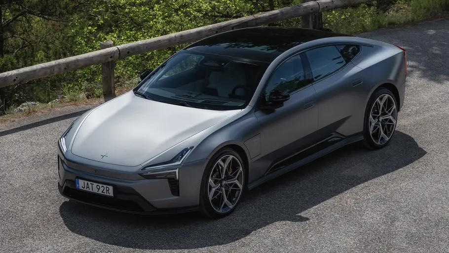 Polestar 5 steht an einem Aussichtspunkt in bewaldeten Bergen. Ansicht von vorne oben links.