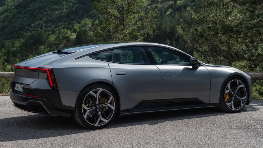 Polestar 5 steht an einem Aussichtspunkt in bewaldeten Bergen. Ansicht von der rechten Seite.