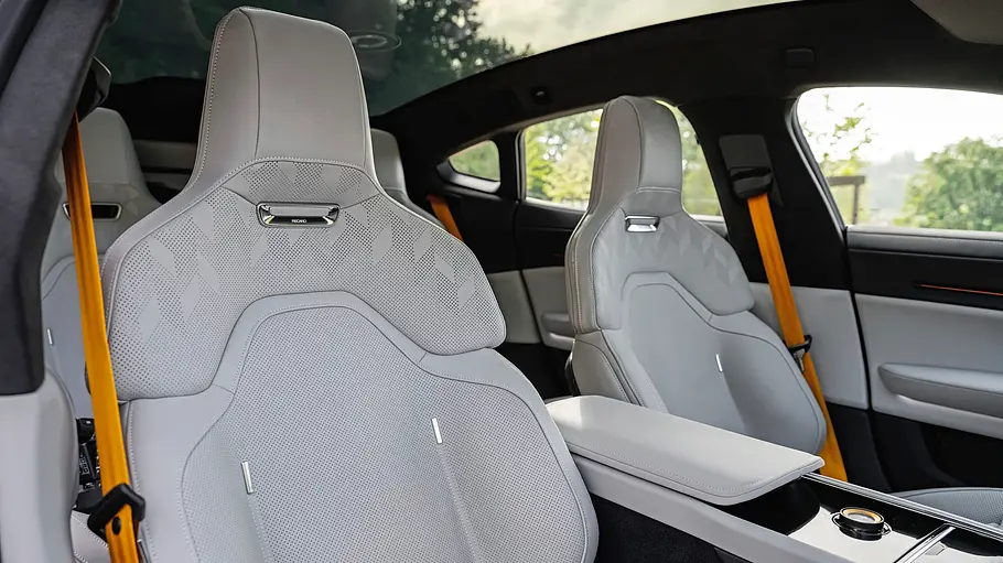 Der Innenraum des Polestar 5 Performance hat hellgraue Sportsitze, gelbe Sicherheitsgurte, eine breite Mittelkonsole und ein Panorama-Glasdach.