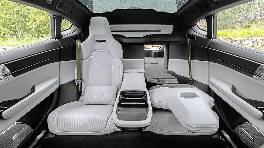 Der helle Fond des Polestar 5 Performance hat eine Mittelkonsole, eine rechts umgeklappte Sitzlehne und ein Panorama-Glasdach mit Regentropfen.
