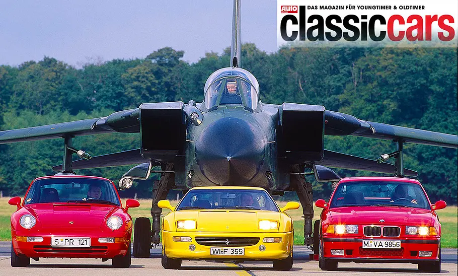 Der Porsche 911 Carrera 2/Ferrari F355/BMW M3 (E36) statisch von vorne fotografiert. Dahinter ein Tornado-Kampfjet.