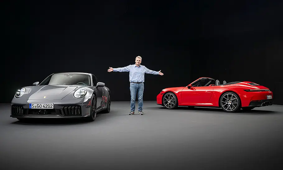 Der Porsche 911 statisch von vorne sowie das Porsche 911 Cabrio statisch von hinten gezeigt, dazwischen AUTO ZEITUNG-Redakteur Martin Urbanke.