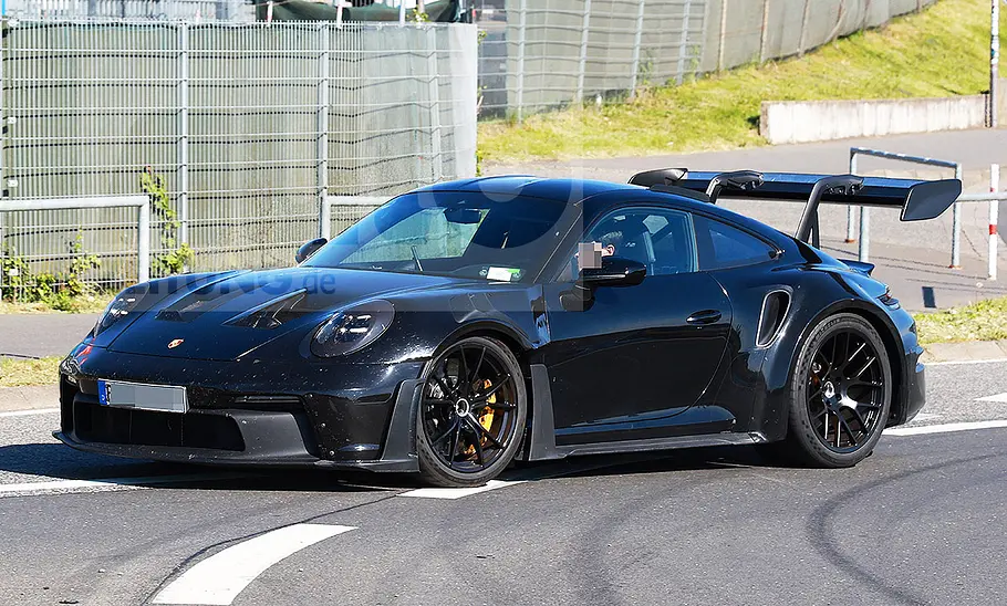 Blick von der Seite auf den Porsche 911 GT2 RS (2026), der auf einer Straße entlangfährt.