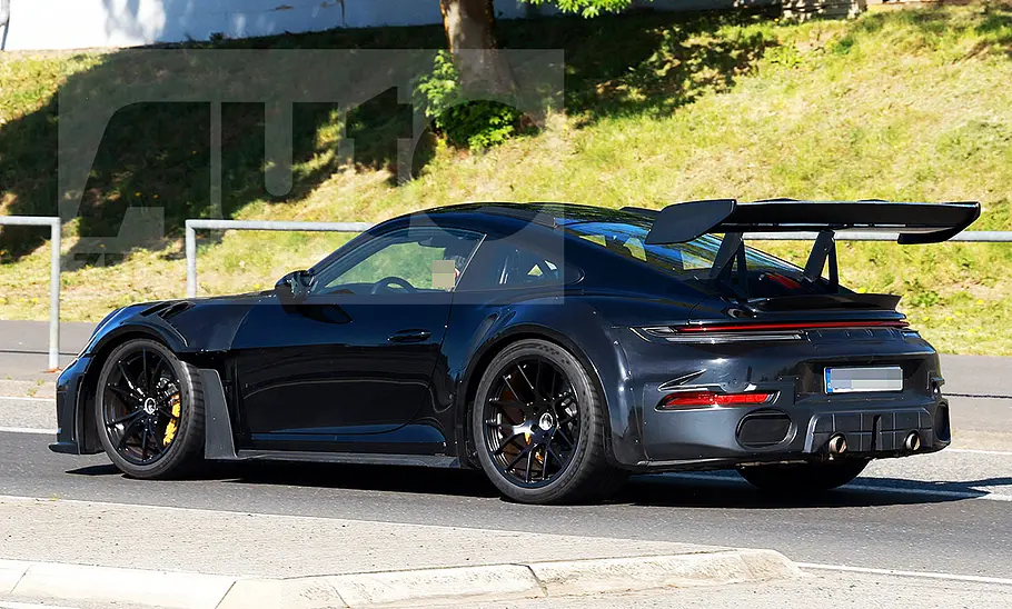 Blick von schräg hinten auf den Porsche 911 GT2 RS (2026), der auf einer Straße entlangfährt.