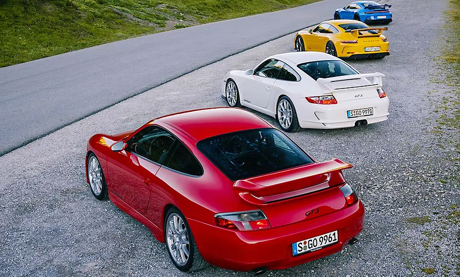 Porsche 911 GT3 Alle Porsche 911 GT3-Generationen stehen aufgereiht auf einem Parkplatz.