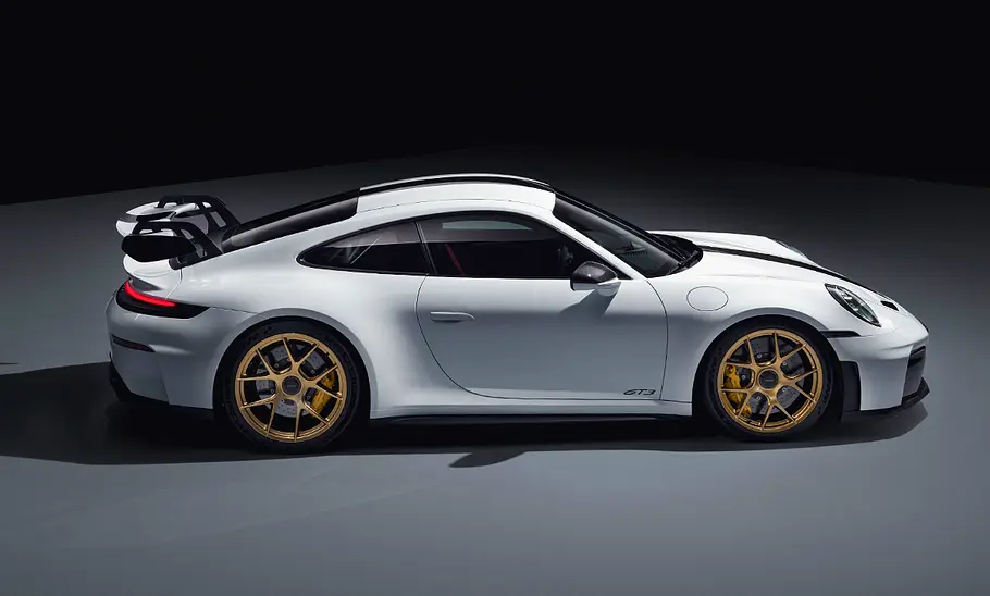 Porsche 911 (992) GT3 Facelift (2024): Weißer Sportwagen steht vor dunklem Hintergrund. Blick auf die Fahrzeugseite.