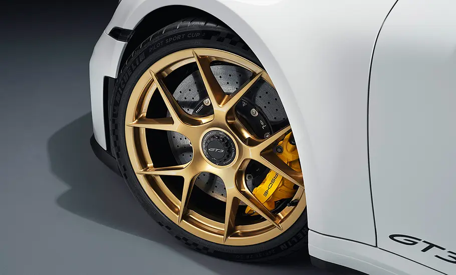 Porsche 911 (992) GT3 Facelift (2024): Weißer Sportwagen steht vor dunklem Hintergrund. Detailanblick auf die Räder.