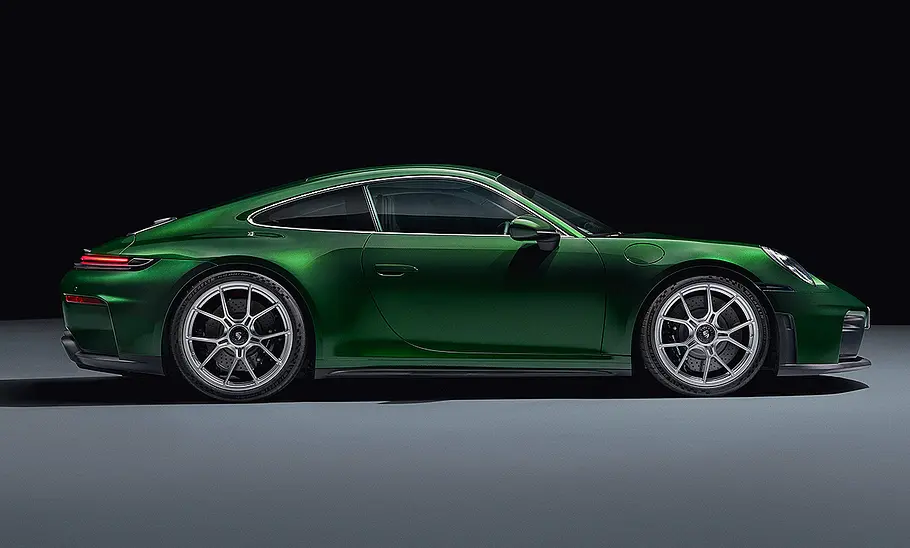 Porsche 911 (992) GT3 Touring Facelift (2024): Grüner Sportwagen steht vor dunklem Hintergrund. Blick auf die Fahrzeugseite.