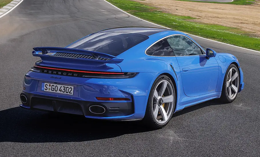 Der Porsche 911 Turbo S (2025) steht auf einer Rennstrecke, fotografiert von schräg hinten.