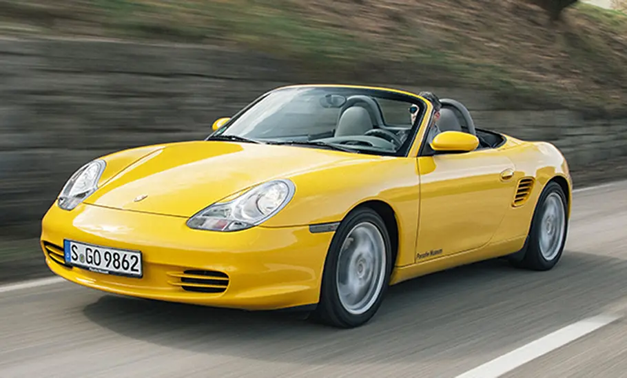 Ein gelber Porsche Boxster fahrend auf einer Straße.